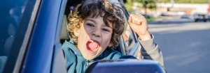 A child sitting behind the steering wheel of a car who portrays whether you are getting gold medal services from your auto-insurance company