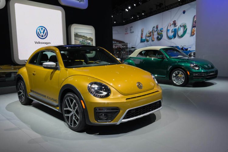 VW Beetle Dune Concept Car on display in a VW auto show. Behind it, a convertible Beetle also on display.