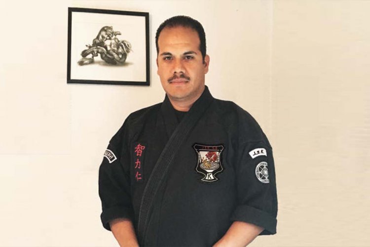 Front view of smiling man, Maurice Gomez, a Women's Self Defense Workshop Leader wearing martial arts uniform