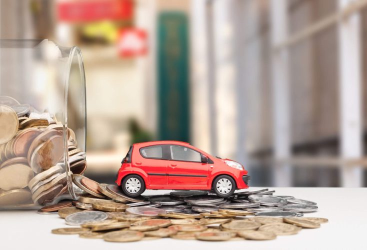 Toy car on top of a bunch of coins that have fallen out of a tilted jar.