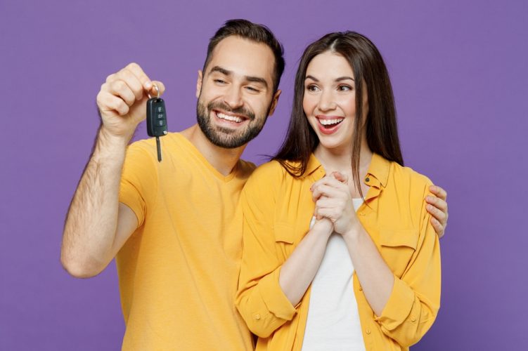 Young couple holds up keys to new car