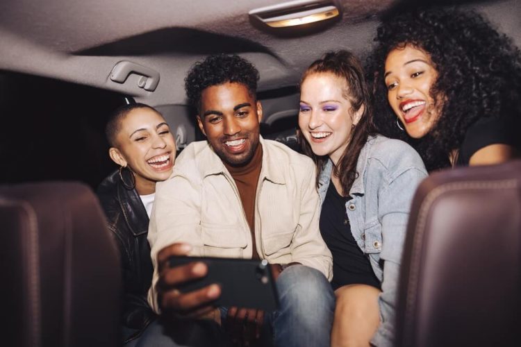 Friends in the backseat of their rideshare take a selfie - cheap rideshare insurance.