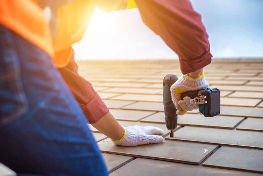 Man using a drill to repair a house roof