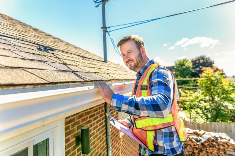 Insurance adjuster inspecting a house roof to determine coverage eligibility - Freeway, affordable homeowners insurance