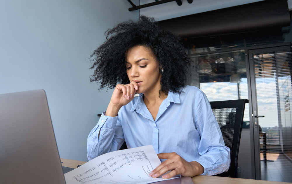 Concerned young woman looking over her car insurance bill.