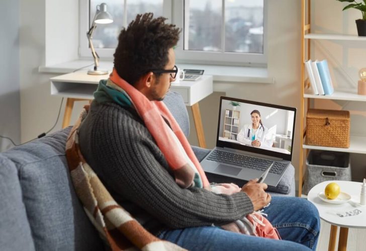 Sick man talks to doctor on his laptop.