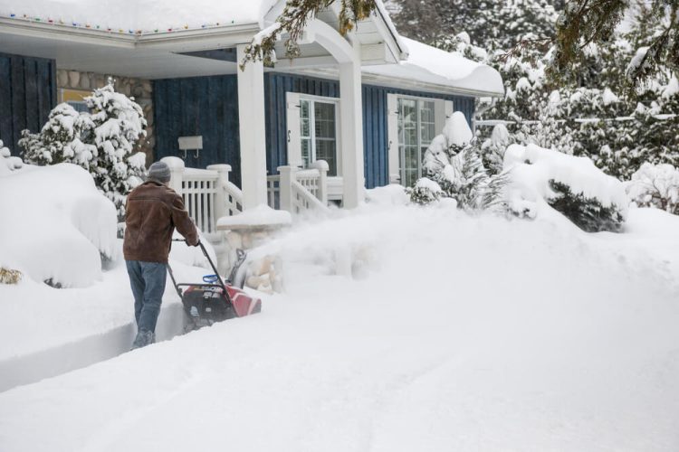 A man cleaning the snow off his home and thinking about his home insurance- Freeway, homeowners insurance